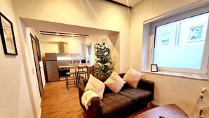 A compact living space with a kitchenette, a sofa, and a small table. - Luxury 2 bedrooms flat (Luxembourg City)