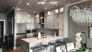 Una cucina moderna con mobili bianchi, elettrodomestici in acciaio inossidabile e un'isola centrale con sgabelli da bar.
