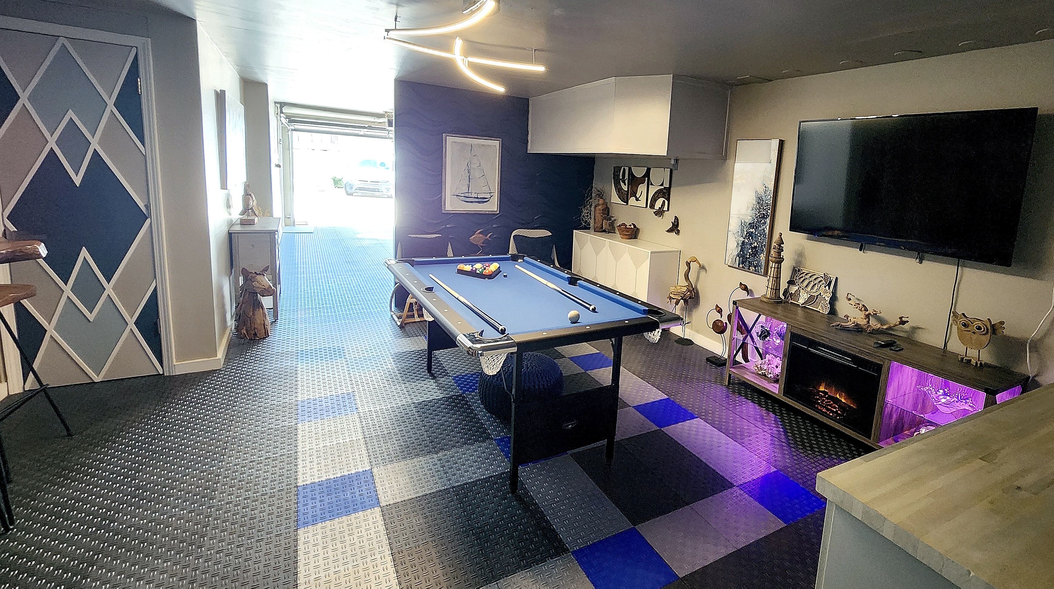 Een biljart in een ruimte met een geruite vloer, een televisie en diverse decoraties.