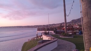 A curved stone pathway leading to a waterfront area with a view of a town in the background. - Olas ocean suite, pool, jacuzzi, bbq & terrace..Pet friendly, gated & secure (Primo Tapia)