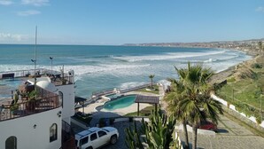A coastal property with a pool, a white car, and a view of the ocean. - Olas ocean suite, pool, jacuzzi, bbq & terrace..Pet friendly, gated & secure (Primo Tapia)