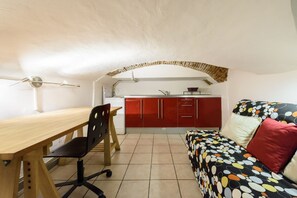 A compact room with a kitchenette, a dining table with chairs, and a sofa with a polka dot cover. - Pepi Red apartment in Florence by Mmega (Firenze)