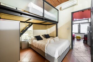 A compact hotel room with a bunk bed, a desk, a chair, and a small stool. - Pepi Red apartment in Florence by Mmega (Firenze)