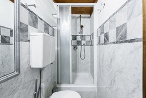 A bathroom with a shower, toilet, and marble tiles. - Pepi Red apartment in Florence by Mmega (Firenze)