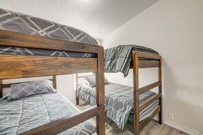 Una cama litera con estructura de madera y ropa de cama gris.
