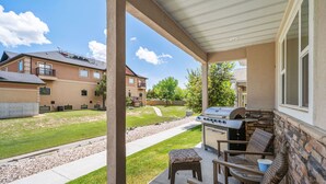 A covered patio with a grill, seating, and a view of the neighborhood.