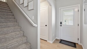 A staircase leading to a landing with a white door and a window with blinds.