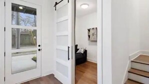 Een modern interieur met een schuifdeur naar een balkon, een trap en een zwarte leren bank.