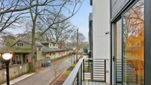 Een modern gebouw met een balkon dat uitkijkt op een woonstraat.