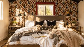 A bedroom with a patterned wallpaper, a wooden bed, and a window with daylight.