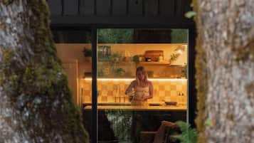 Una cocina moderna con una persona cocinando, rodeada de paredes de madera y un gran tronco de árbol.