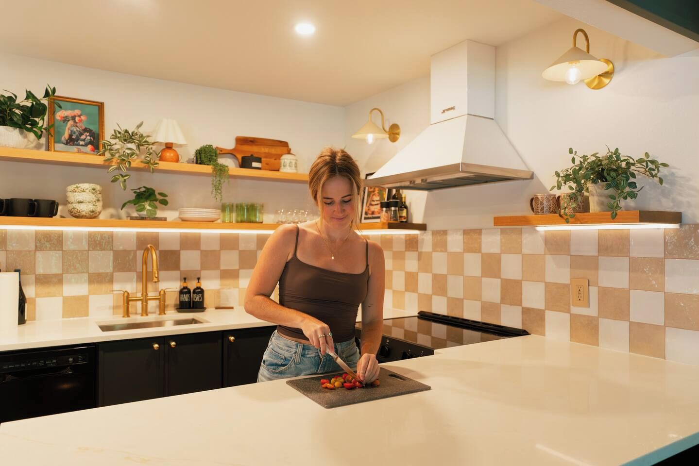 A modern kitchen with a woman preparing food, featuring a checkered backsplash, a white stove, and various kitchen appliances.