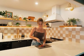 Eine moderne Küche mit einer Frau, die Essen zubereitet, mit karierter Spritzschutzleiste, einem weißen Herd und verschiedenen Küchengeräten.