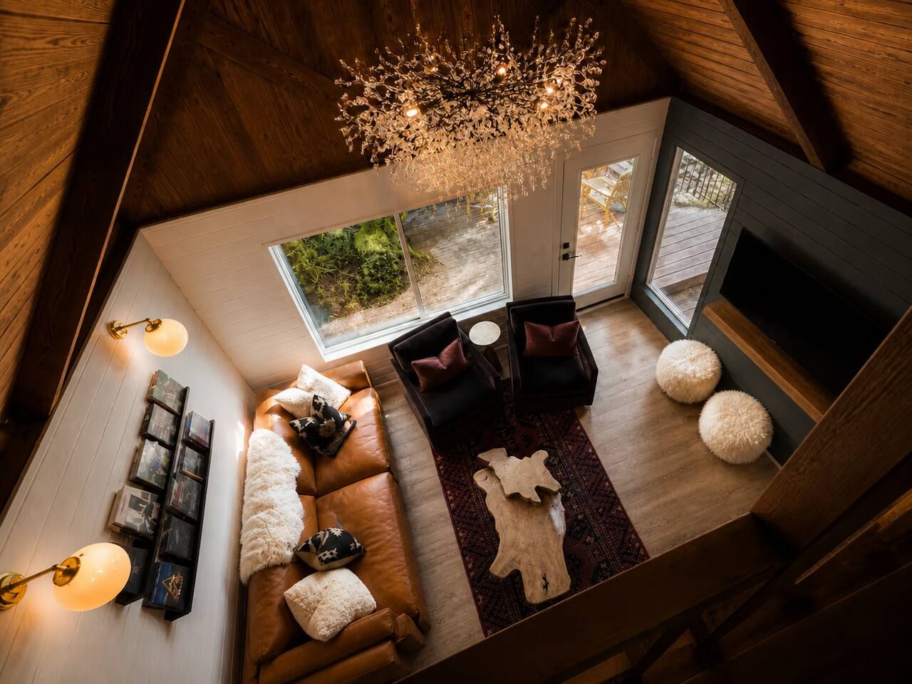 Un soggiorno in stile loft con soffitto in legno, camino, divano, tavolino da caffè e lampadario.