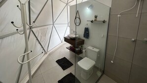 Kompakti ja moderni kylpyhuone, jossa on lasinen suihkuseinä, pesuallas ja wc.