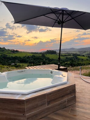 A hot tub on a wooden deck with a view of a sunset over rolling hills. - Domo Geodésico - Conforto e Relaxamento na Natureza (Socorro)