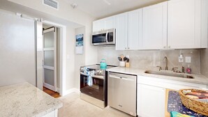 A modern kitchen with white cabinets, a microwave, a dishwasher, and a sink. - Newly remodeled house in San Marco few minutes walk to Square  & Riverwalk (Jacksonville)