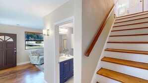 A hallway with a wooden staircase, a door, a window with a view, and a bathroom with blue cabinets. - Newly remodeled house in San Marco few minutes walk to Square  & Riverwalk (Jacksonville)