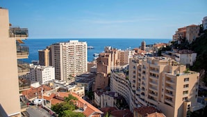 A coastal cityscape with high-rise buildings, a clear sky, and the sea in the background. - Appartement 7B - MyResidenced'Azur (Beausoleil)