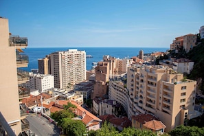 A coastal cityscape with high-rise buildings, a clear sky, and the sea in the background.