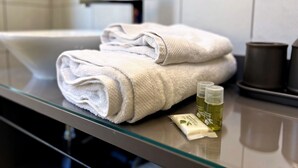 A bathroom with a glass countertop, a white sink, and two bottles of lotion. - Appartement 7B - MyResidenced'Azur (Beausoleil)