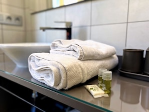 A bathroom with a glass countertop, a white sink, and two bottles of lotion.