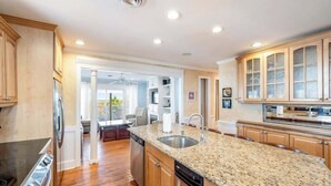 A modern kitchen with granite countertops, stainless steel appliances, and wooden cabinets. - A Shore Thing - Oceanfront - Hot Tub -Pet Friendly (Carolina Beach)