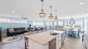 Amplia sala de estar con una isla grande, una mesa de comedor y una cocina con un lavamanos.