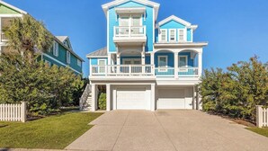 A two-story house with a front garage, a balcony on the second floor, and a well-maintained lawn. - Seaside Palace (Kure Beach)