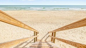 A wooden staircase leading to a sandy beach with the ocean in the background. - No Cleaning Fee - 6BR Oceanfront - Oceanfront - Pool (Carolina Beach)