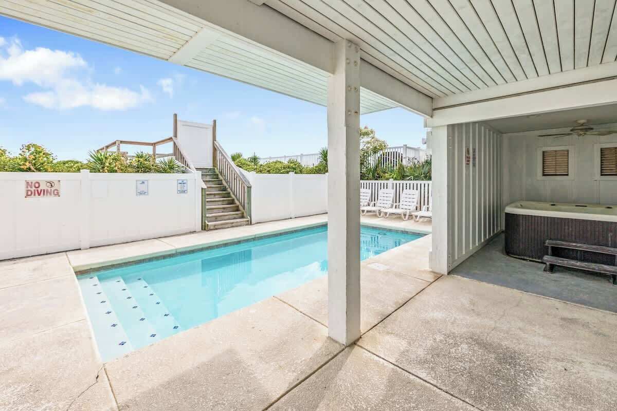 A swimming pool with a no diving sign, a covered patio area, and a hot tub.