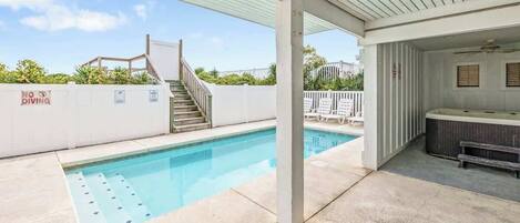 A swimming pool with a no diving sign, a covered patio area, and a hot tub.