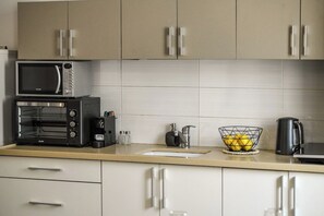 A kitchen with a microwave, toaster, sink, and a bowl of lemons on the counter. - The Printhouse Boutique Studio 5 by SeaNRent (Haifa)