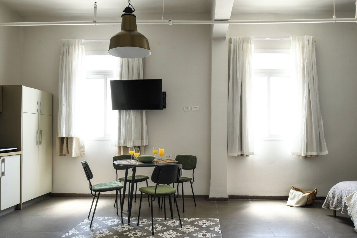 Ein kleines Zimmer mit Esstisch, Stühlen, einem Flachbildfernseher und einem Bett.