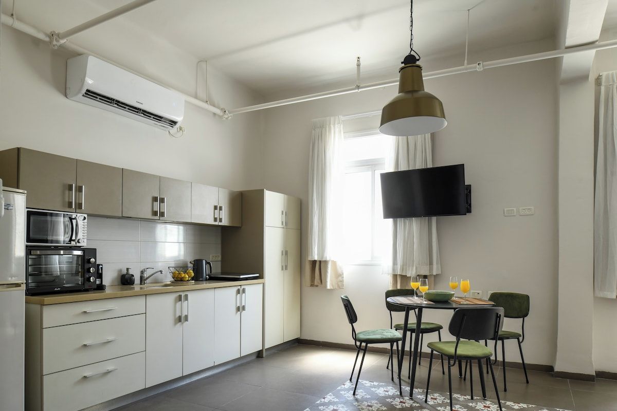 Una cucina moderna con una TV a schermo piatto, un forno a microonde e un'area pranzo con sedie e tavolo.