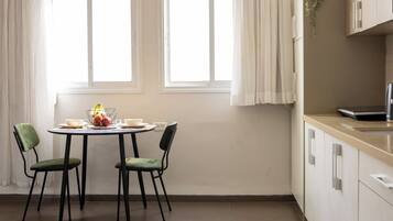 Une cuisine comprenant un coin repas, avec une table et des chaises, un réfrigérateur et des placards.