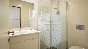 Ein Badezimmer mit einer Duschkabine, einem weißen Waschbecken und einer Toilette.