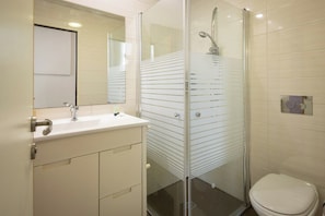 A bathroom with a glass-enclosed shower, a white sink, and a toilet.