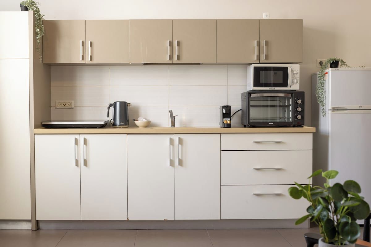 A kitchen with beige cabinets, a microwave, a toaster, and a refrigerator.
