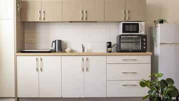 A kitchen with beige cabinets, a microwave, a toaster, and a refrigerator.