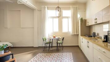 A compact kitchen with a dining area, a hanging light fixture, and a window with curtains.
