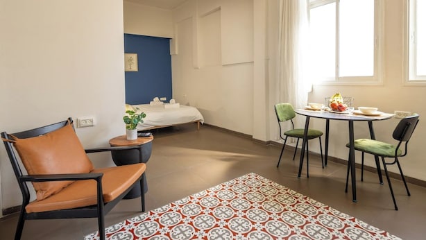 Ein Hotelzimmer mit einem Bett, einem kleinen Tisch mit Stühlen, einem Fenster mit Vorhängen und einem dekorativen Teppich.