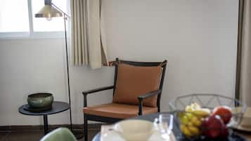 Una habitación con una silla, una mesita, un cuenco y una frutera, además de una lámpara.