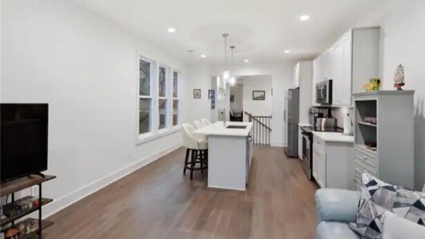 A spacious living area with a kitchen, dining area, and a TV on a stand.