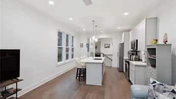 A spacious living area with a kitchen, dining area, and a TV on a stand.