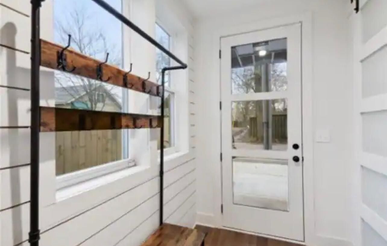 A hallway with a wooden bench, a white door, and a window.
