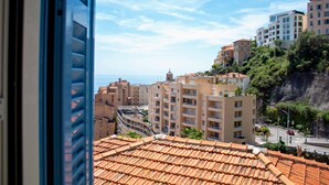 A coastal cityscape with terracotta-roofed buildings, a prominent church, and a clear view of the sea.