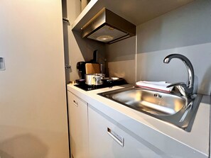 A compact kitchen with a sink, a coffee maker, and a toaster.