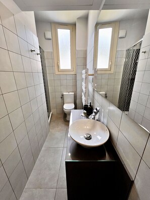 Een moderne badkamer met een groot wastafel, toilet en douche.