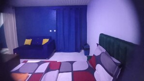 Una habitación con una cama, un sofá azul y un cubo de basura.